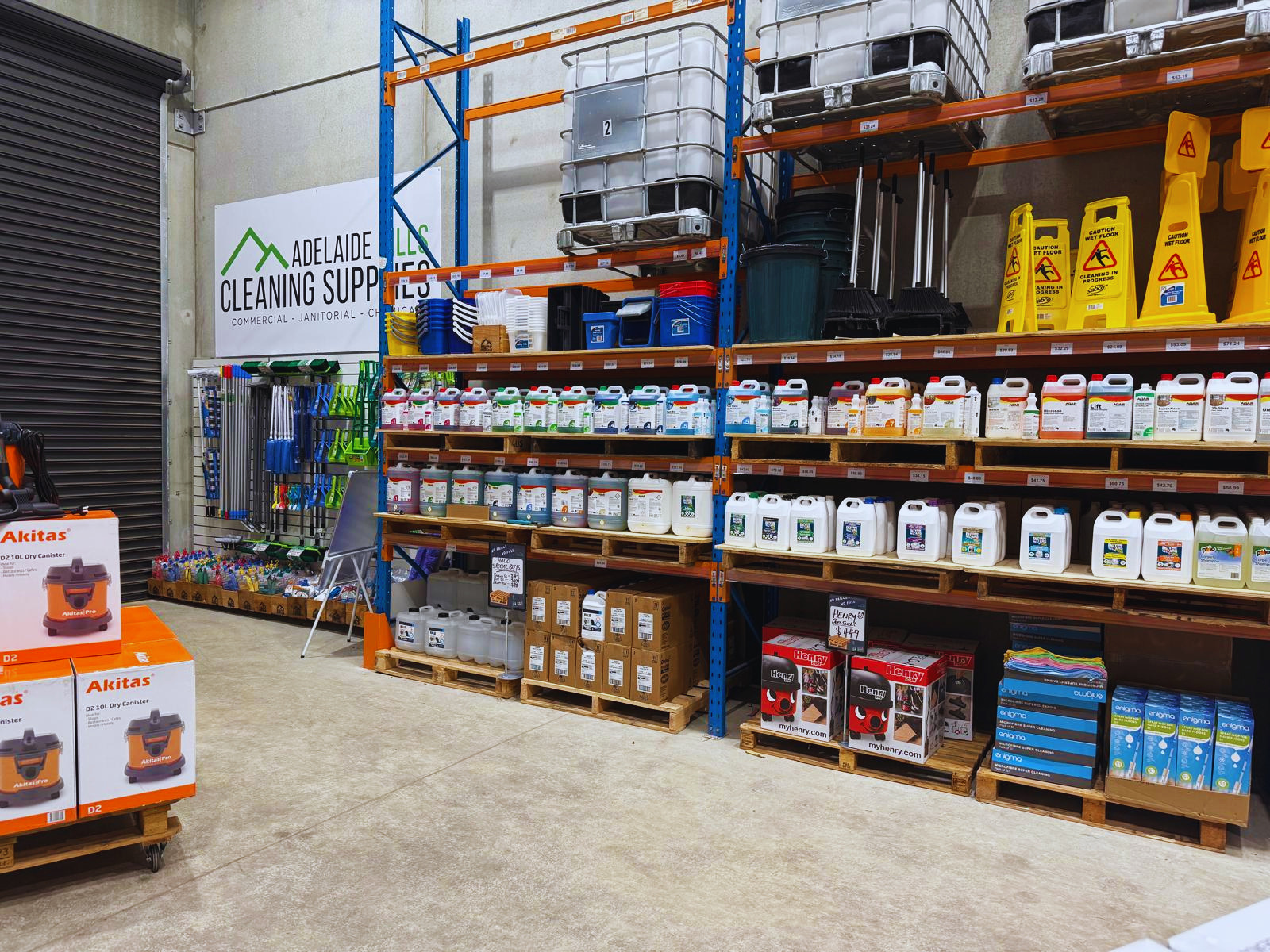 Storage warehouse with shelves stocked with commercial cleaning supplies and equipment including Oates Research Products Halo, Edco, Agar, Akitas, Enzyme Wizard, Sabco